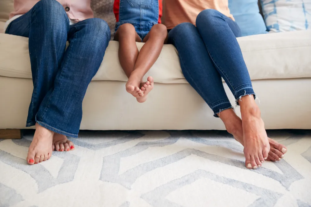 Close Up Of Multi-Generation Female Hispanic Family Sitting On Sofa At Home