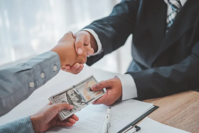 Customer shaking hands with a man in a suit. The other hand is exchanging money from the business man to the customer.