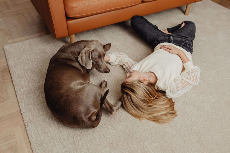 Woman lying on soft carpet next to a dog in a modern living room — showing why carpet remains a practical, comfortable flooring choice for Texas family homes in 2026