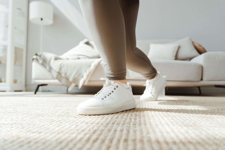 Person walking on soft neutral carpet with quality foam padding, showcasing comfort benefits of residential foam versus commercial rubber padding